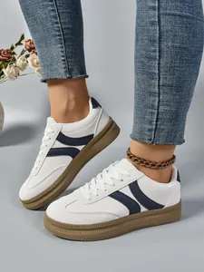 Baskets compensées blanches pour femmes avec détails bleu marine et semelles brunes.
