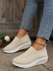 Side view detail of beige breathable fly-knit slip-on sneakers with platform wedge soles