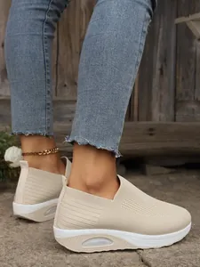 Detail view of beige fly-knit slip-on sneakers featuring a thick air cushioned rocker sole