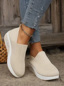 Detailed on-feet view of beige flyknit slip-on sneakers with a comfortable thick air-cushioned sole.