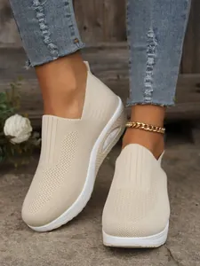 Close-up of beige breathable fly-knit slip-on sneakers with thick air cushion soles