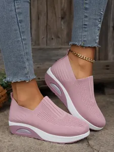 Close-up of pink breathable fly-knit platform sneakers for women in a street setting