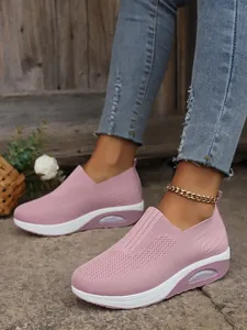 Close-up of pink flyknit platform walking sneakers worn with denim jeans outdoors