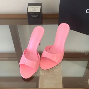 Stylish pink patent leather high-heel mule sandals displayed on a modern glass shelf