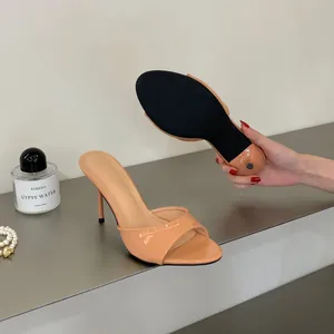 Detailed view of nude patent leather stiletto mules showing the black anti-slip sole