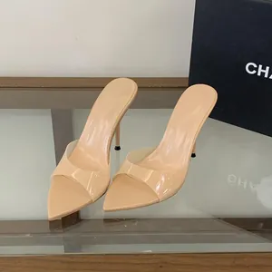 Primo piano di sabot beige a punta con cinturini trasparenti e alti tacchi a spillo