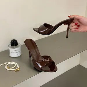 Elegant coffee brown patent leather high heel mules displayed on a grey shelf