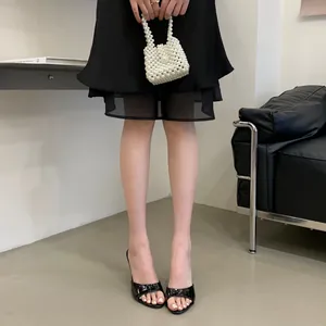 Close-up view of elegant black patent leather high heel mule sandals worn by model