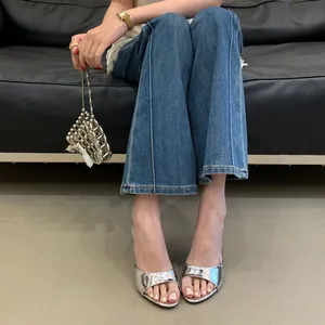 Close-up detail of metallic silver high-heel mule sandals worn with blue flared jeans