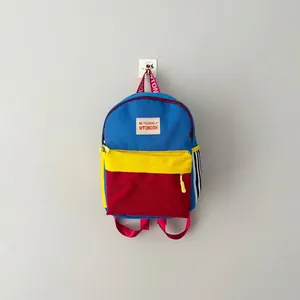 Vista dettagliata di uno zaino colorato per bambini appeso a un muro grigio.