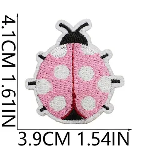 Vista dettagliata di una toppa ricamata a forma di coccinella rosa con misure precise.