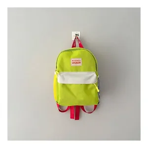 Zainetto per bambini verde vivace con spallacci rossi e tasca anteriore bianca.
