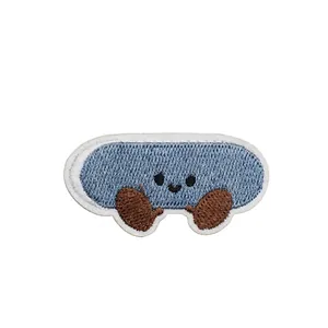 Close-up of a blue cartoon embroidered patch featuring a smiley face and dimension labels