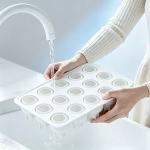 Witte siliconen bakvorm met 15 holtes die wordt afgespoeld onder een schone kraan.