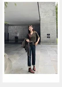 Vista completa de una modelo con botines de ante marrón en un entorno exterior minimalista