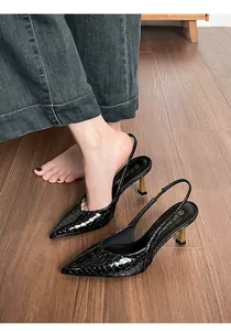Close-up of black crocodile embossed pointed-toe slingback heels with gold stiletto.