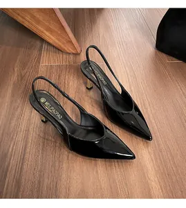 Detailed top view of black patent leather slingback heels on wooden floor