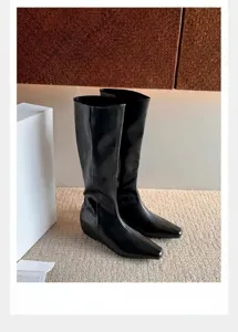 Detalle de botas de cuero negro minimalistas con punta cuadrada en un ambiente moderno
