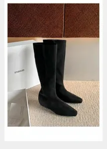 Primer plano de botas de ante negro a media pierna con punta cuadrada y diseño elegante.