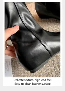 Primer plano detallado de la textura de cuero negro de los botines con cuña oculta de 5 cm