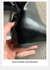 Vista detallada del tacón interno oculto de 5 cm en botines de cuero negro suave.