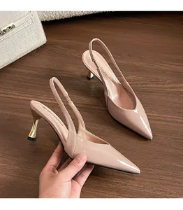 Close-up of elegant nude patent leather pointed-toe slingback heels with gold kitten heels