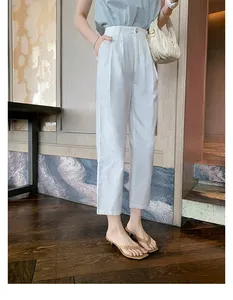 Nahaufnahme von eleganten hellbraunen Leder-Tanga-Sandalen mit Absatz zu weißer Hose