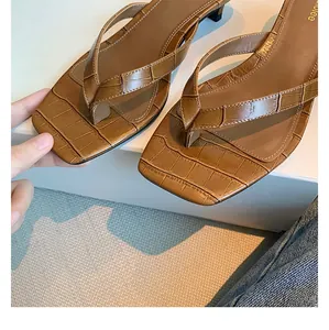Detailansicht von braunen Leder-Zehenstegsandalen mit Krokoprägung und eckiger Zehenpartie.
