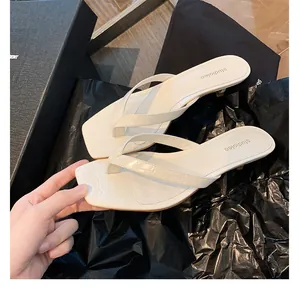 Detailaufnahme eleganter weißer Zehentrenner-Sandaletten aus echtem Leder mit Krokoprägung