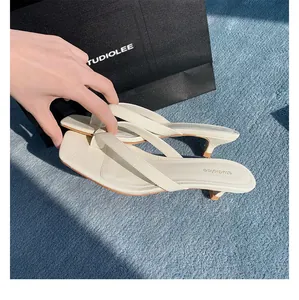 Nahaufnahme der cremefarbenen Leder-Zehenstegsandalen mit Kitten-Heels und Krokoprägung