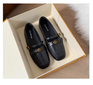 Detailed view of black Mary Jane flat loafers with gold camellia flower ornament