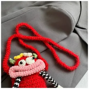 Close-up of handmade red crochet crossbody bag with funny big mouth character face