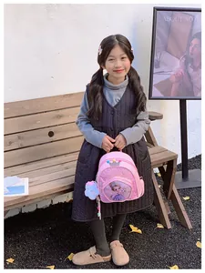 Detail view of pink sequined cartoon backpack held by a young girl outdoors