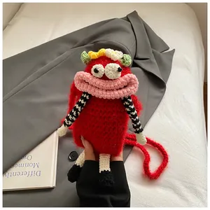 Hand holding a funny red crocheted monster crossbody bag featuring a unique big mouth design
