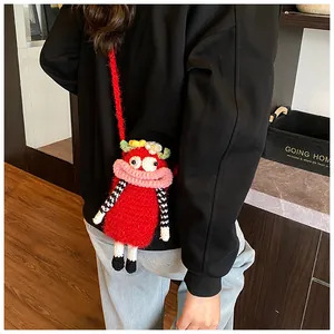 Close-up of a handmade red crochet monster bag worn by a lifestyle model
