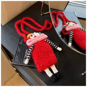 Handmade red crochet phone bag with unique big mouth design resting on a black book