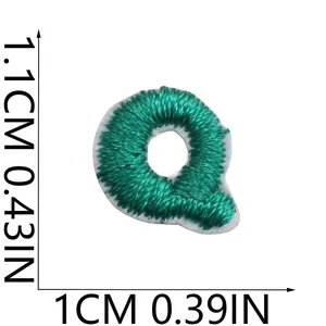 Detailed macro shot of mini green embroidered letter Q patch showing 1.1cm height and width