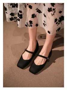 Gros plan de chaussures Mary Jane françaises noires à bout carré avec boucle dorée