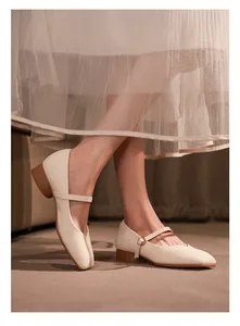 Gros plan de chaussures Mary Jane à bout carré crème portées avec une jupe en tulle