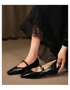 Detaillierte Makroansicht schwarzer Mary Jane Schuhe mit spitzer Kappe und goldener Schnalle