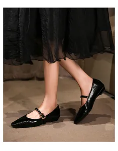 Nahaufnahme schwarzer Mary Jane Ballerinas mit spitzer Kappe und goldener Schnalle.