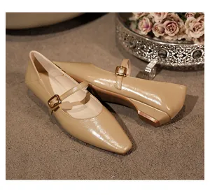 Detailansicht beigefarbener Retro-Mary Janes mit goldener Schnalle und Blockabsatz
