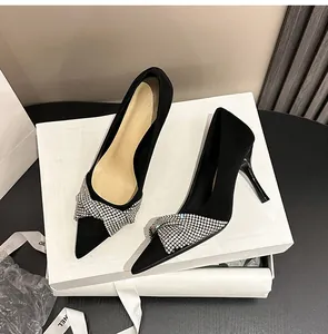 Detail view of elegant black suede high heels featuring a sparkling rhinestone cross strap.
