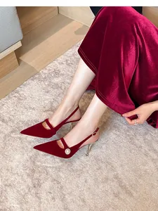 Primer plano de tacones destalonados de ante granate con hebilla de perlas