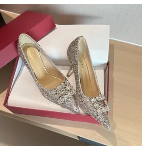 Close-up of elegant champagne glitter high heels with rhinestone buckle in a luxury gift box
