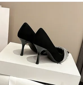 Close-up of elegant black suede stiletto pumps with shimmering rhinestone detailing