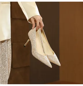 Close-up of sparkling gold glitter pointed-toe stiletto heels held by a hand