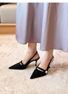 Primer plano de elegantes zapatos de tacón destalonados de ante negro con perla