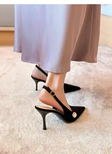 Primer plano de elegantes zapatos de tacón destalonados en ante negro con detalle de perla.