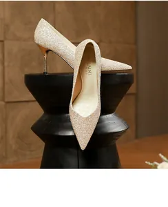 Elegant champagne glitter pointed-toe high heels displayed on a black decorative stand.